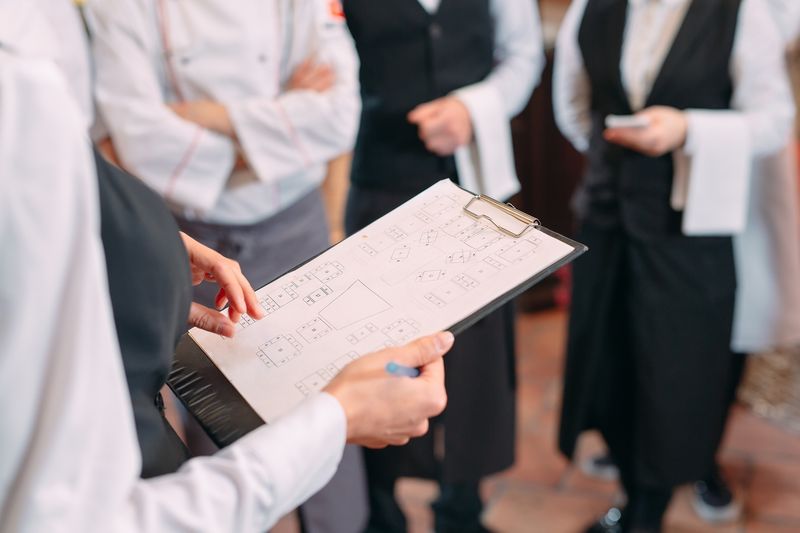 Team in einer Restaurantküche bespricht Unterlagen auf einem Klemmbrett